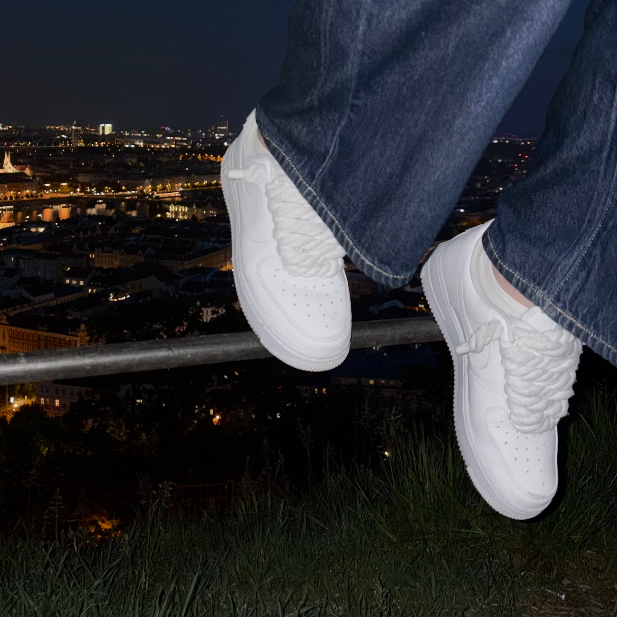 Bílé Nike Air Force 1 s rope laces nad nočním městem – Kosmo Studio
