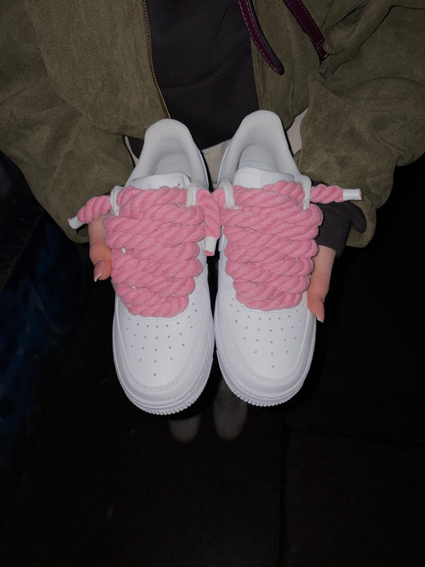 Ruce drží bílé Nike Air Force 1 s růžovými rope laces – Kosmo Studio