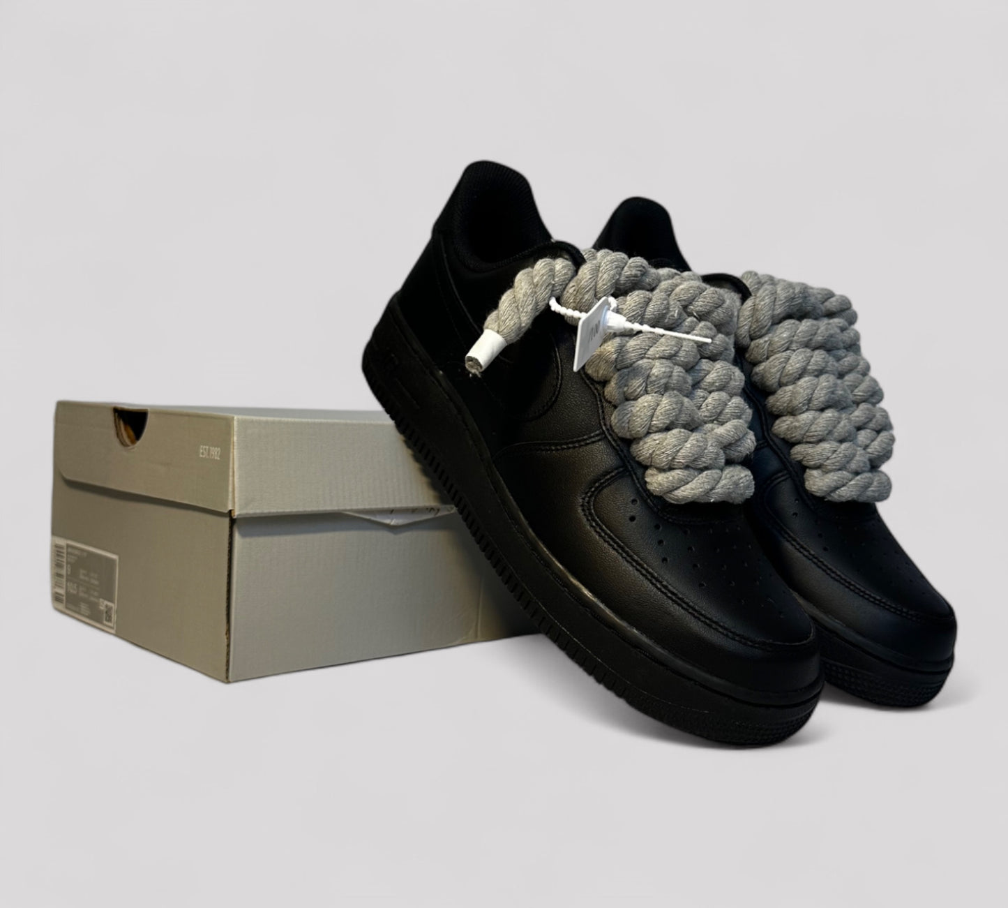 Black shoes with gray rope laces on a light gray background