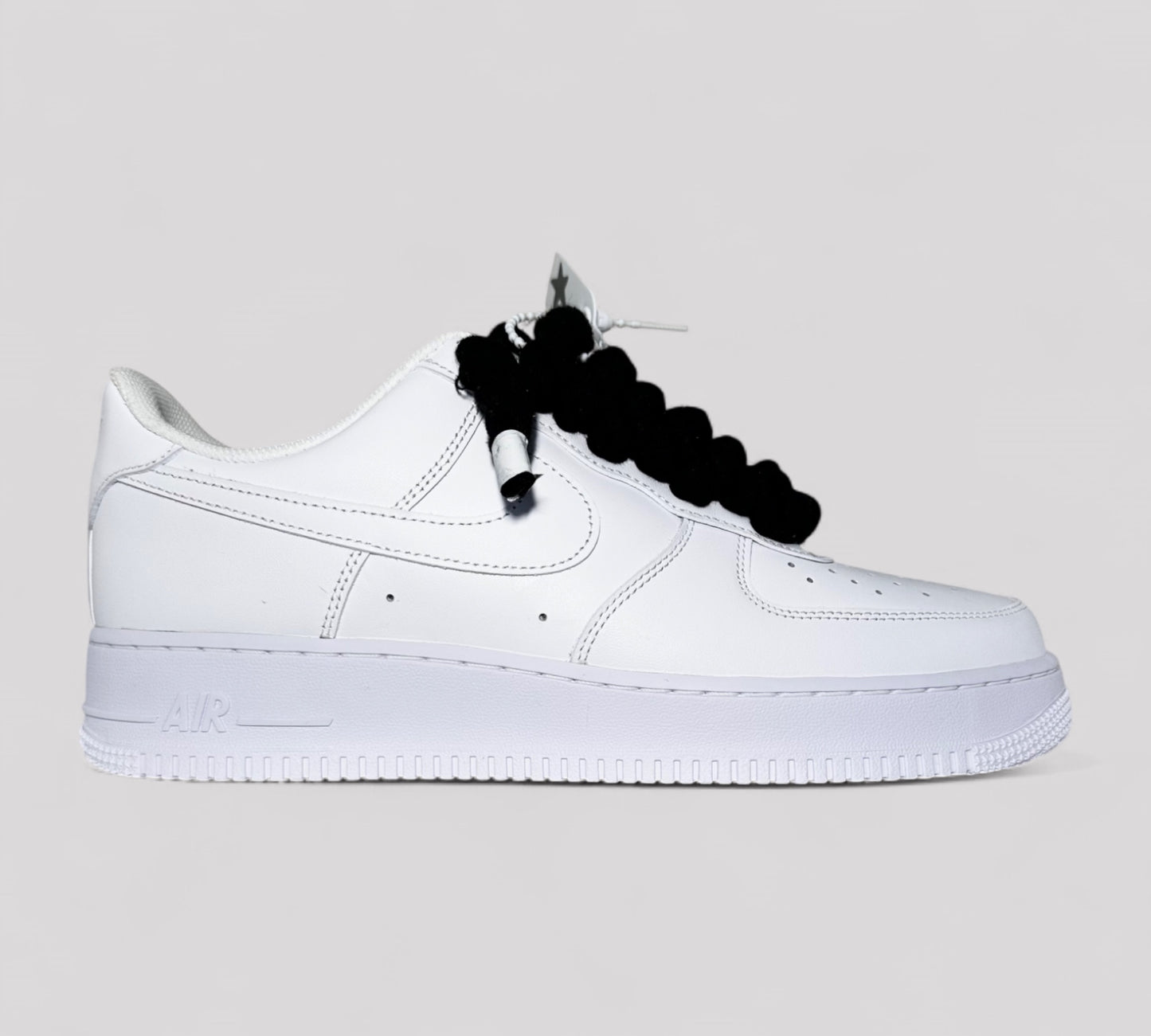 White sneaker with black rope laces from Kosmo studio on a light gray background