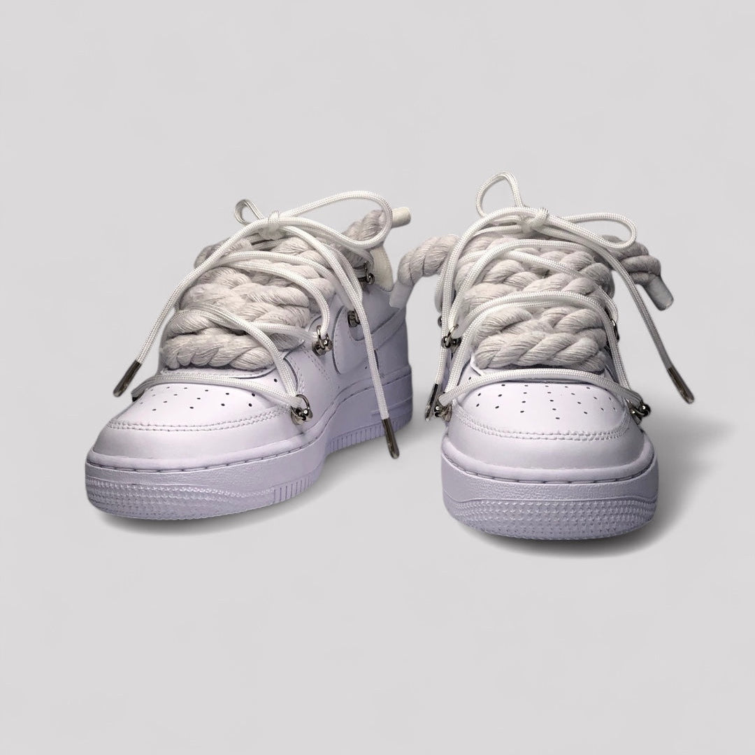 Pair of white sneakers with braided laces on a light gray background