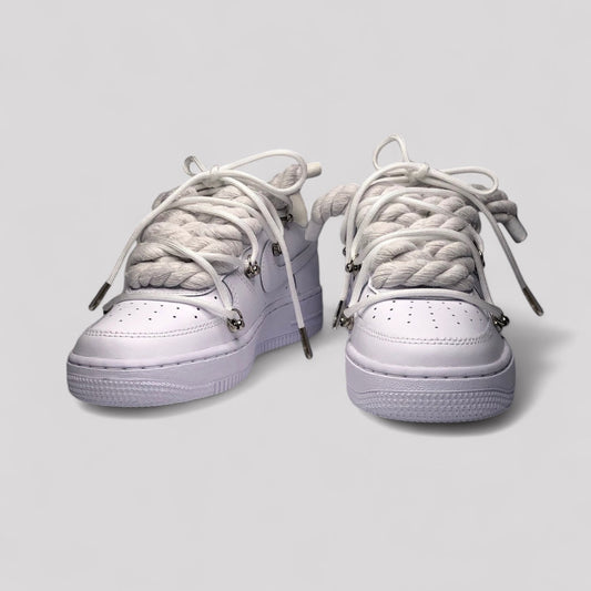 Pair of white sneakers with braided laces on a light gray background