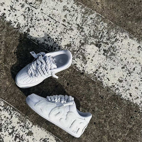 Dvě bílé Nike Air Force 1 s rope laces na přechodu, vpravo Kosmo edition s koženým AIR písmem – Kosmo Studio