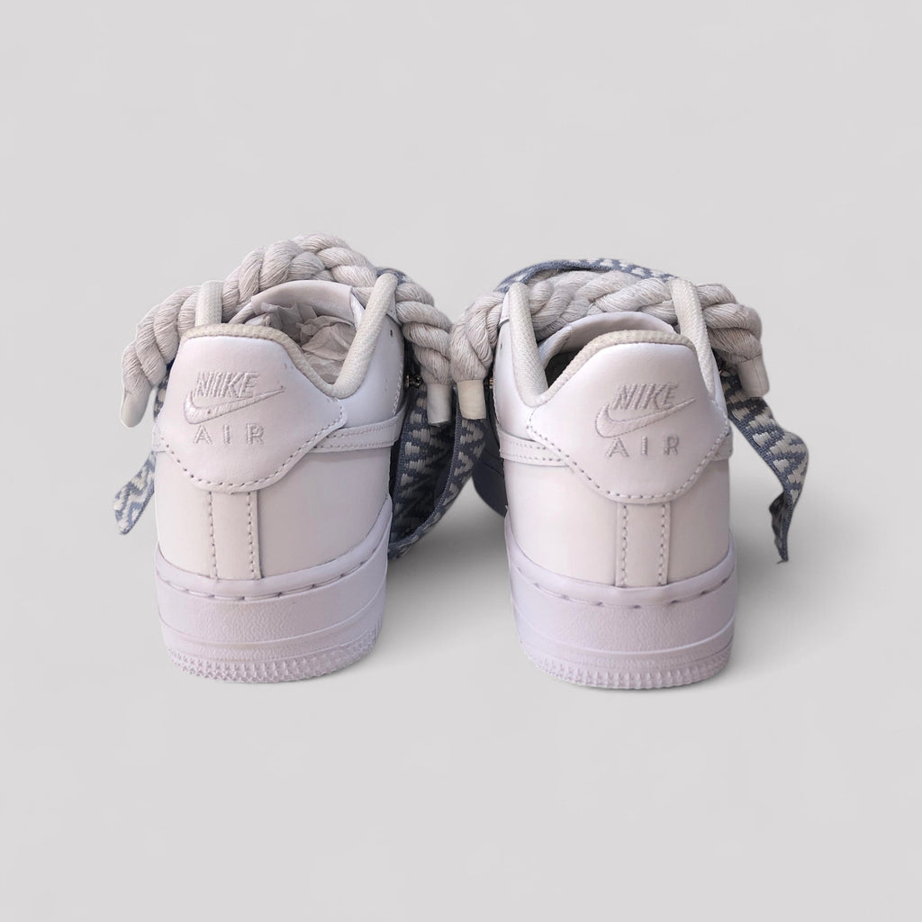 Pair of light purple Nike Air Force sneakers with braided laces on a white background