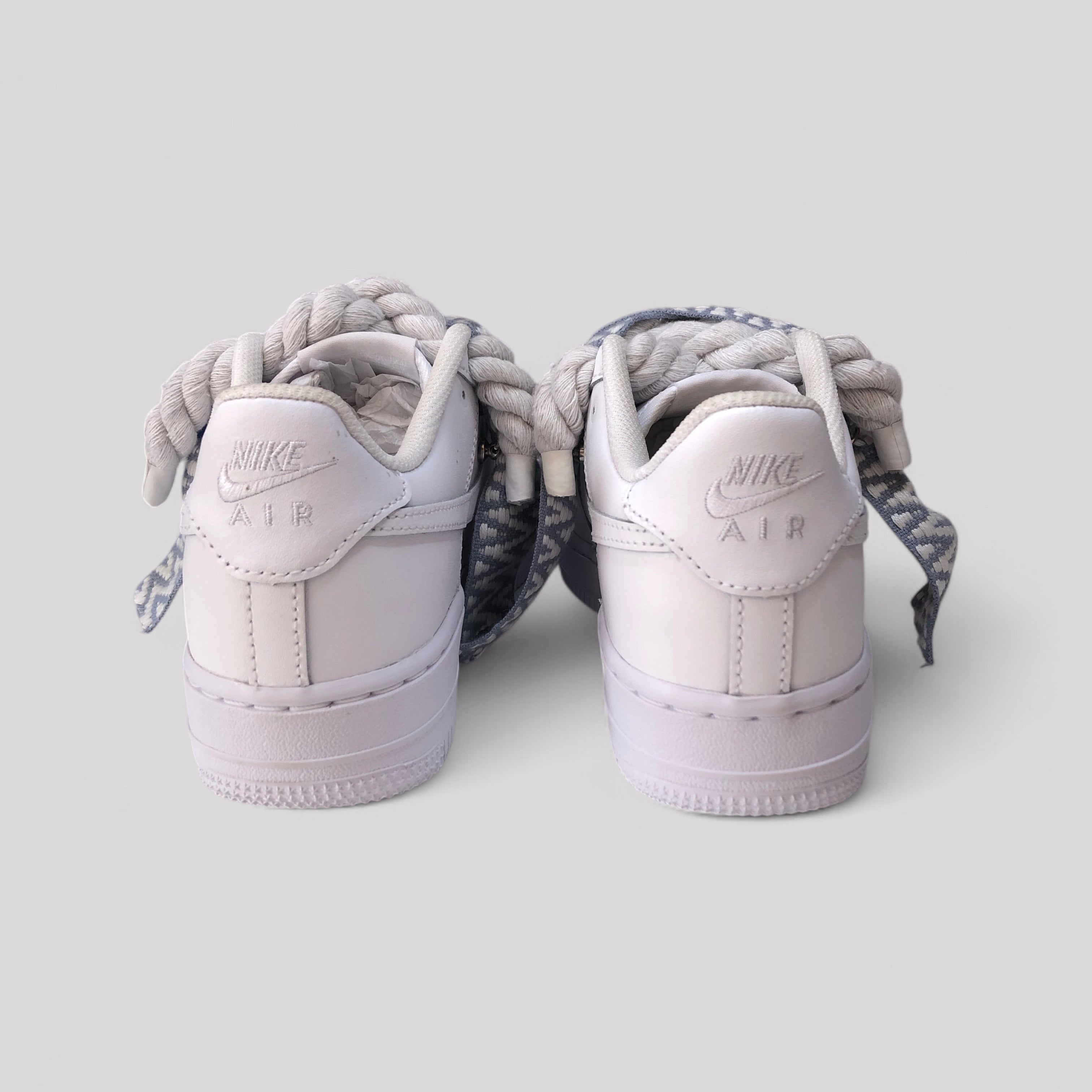 Pair of light purple Nike Air Force sneakers with braided laces on a white background