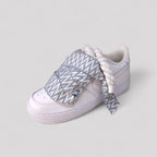 White sneakers with patterned laces on a light gray background