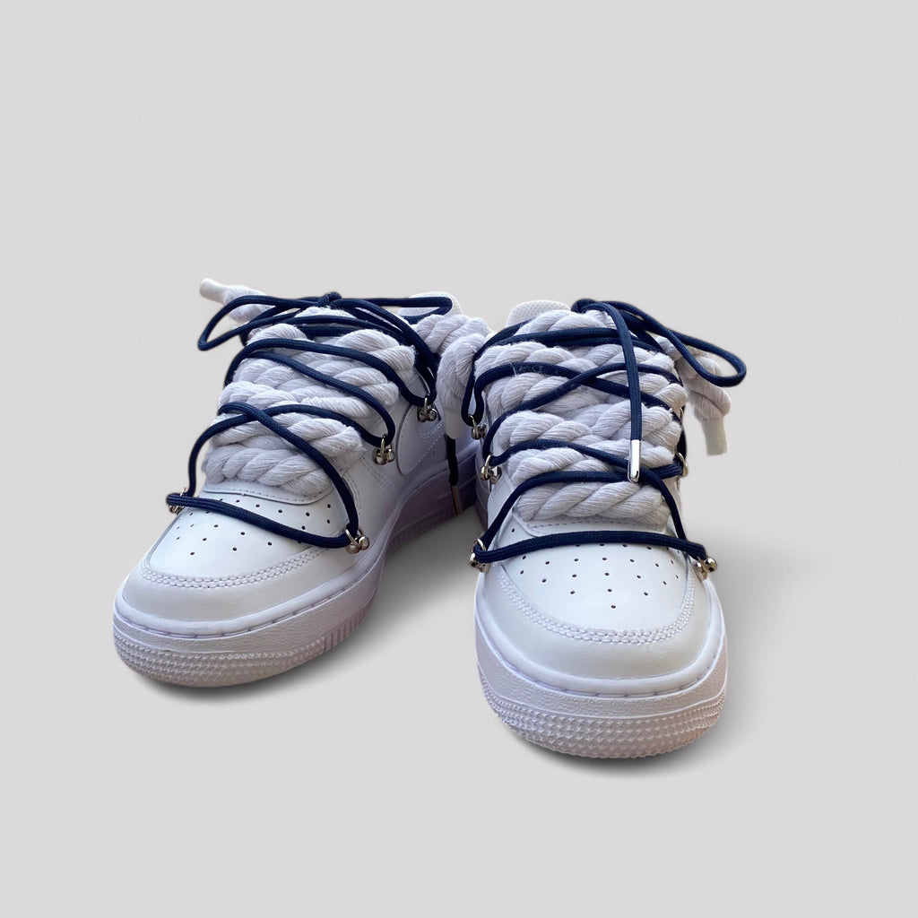 White sneakers with navy blue laces on a light gray background