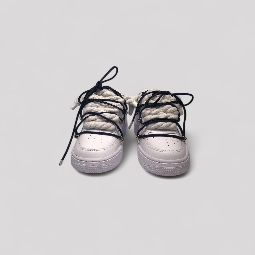 White sneakers with black laces on a light gray background