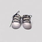 White sneakers with black laces on a light gray background