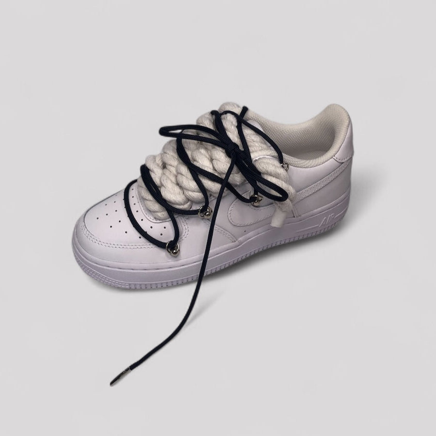 White sneaker with black laces on a light gray background