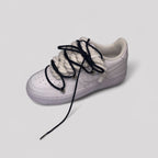 White sneaker with black laces on a light gray background